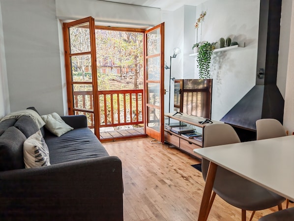 Un espace de vie moderne doté d’un plancher en bois, d’un canapé, d’une table à manger et d’un coin cuisine avec un barbecue.