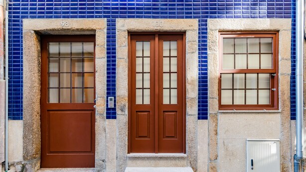Fachada de edificio con dos puertas, con los números 98 y 100, y una ventana de diseño calado.