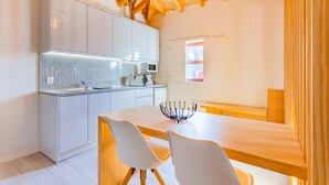 Una cocina moderna con armarios blancos, encimera de granito y comedor con mesa de madera y sillas blancas.