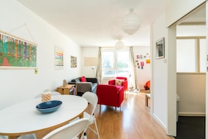 Relax in this stylish living space with a round dining table, comfortable seating, and a large window offering a view of the outdoors.
