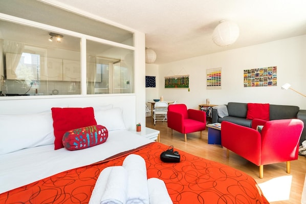 Et moderne værelse med en seng, en rød sofa, en grå sofa og et spiseområde.