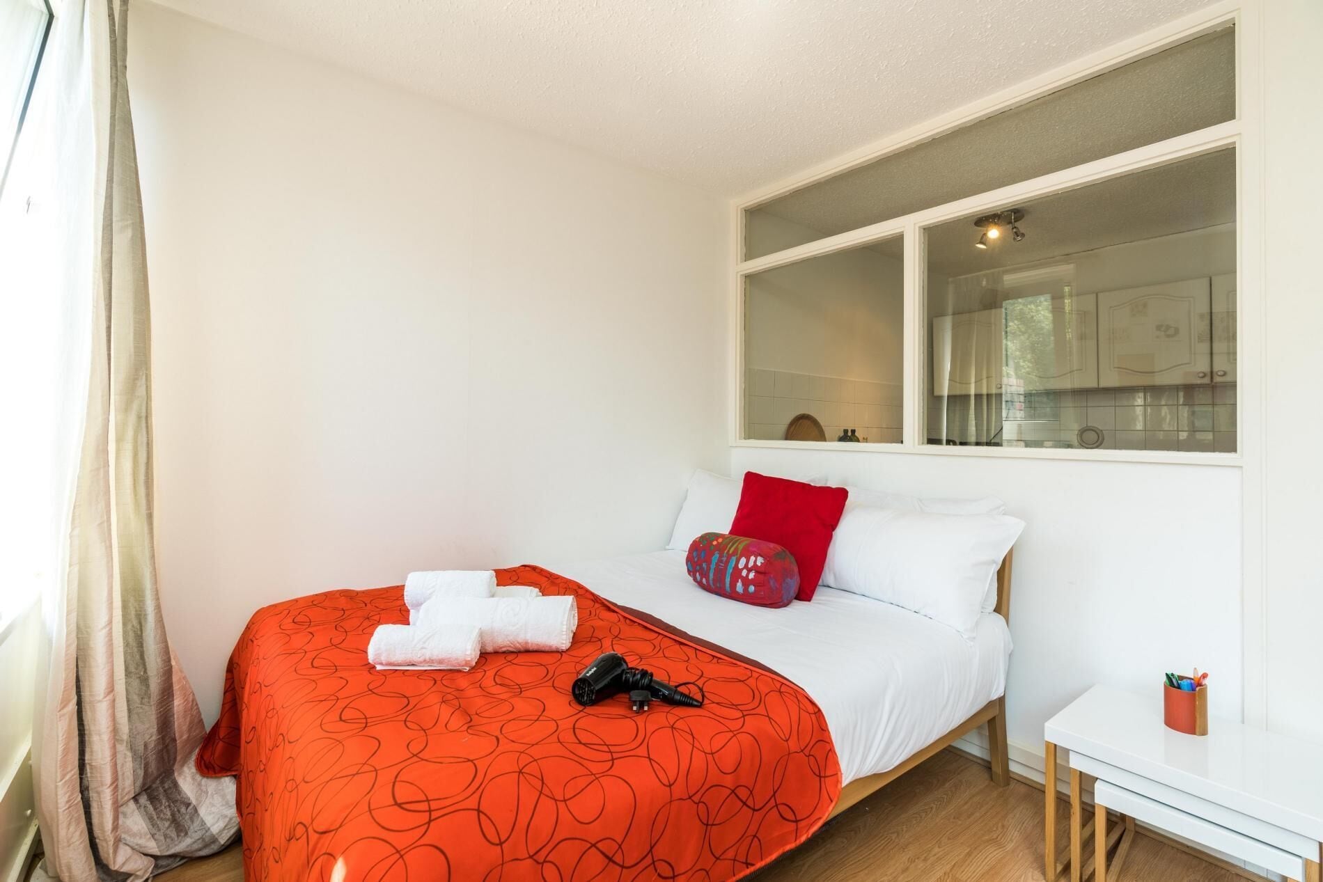 Ein Schlafzimmer mit Bett, Fenster, kleinem Tisch und Nachttisch.