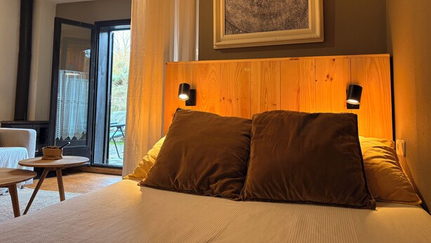 A bedroom with a bed, two bedside lamps, a wooden headboard, and a framed artwork above the bed.