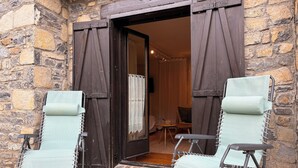 A stone-walled entrance with two light blue chairs and a wooden door.