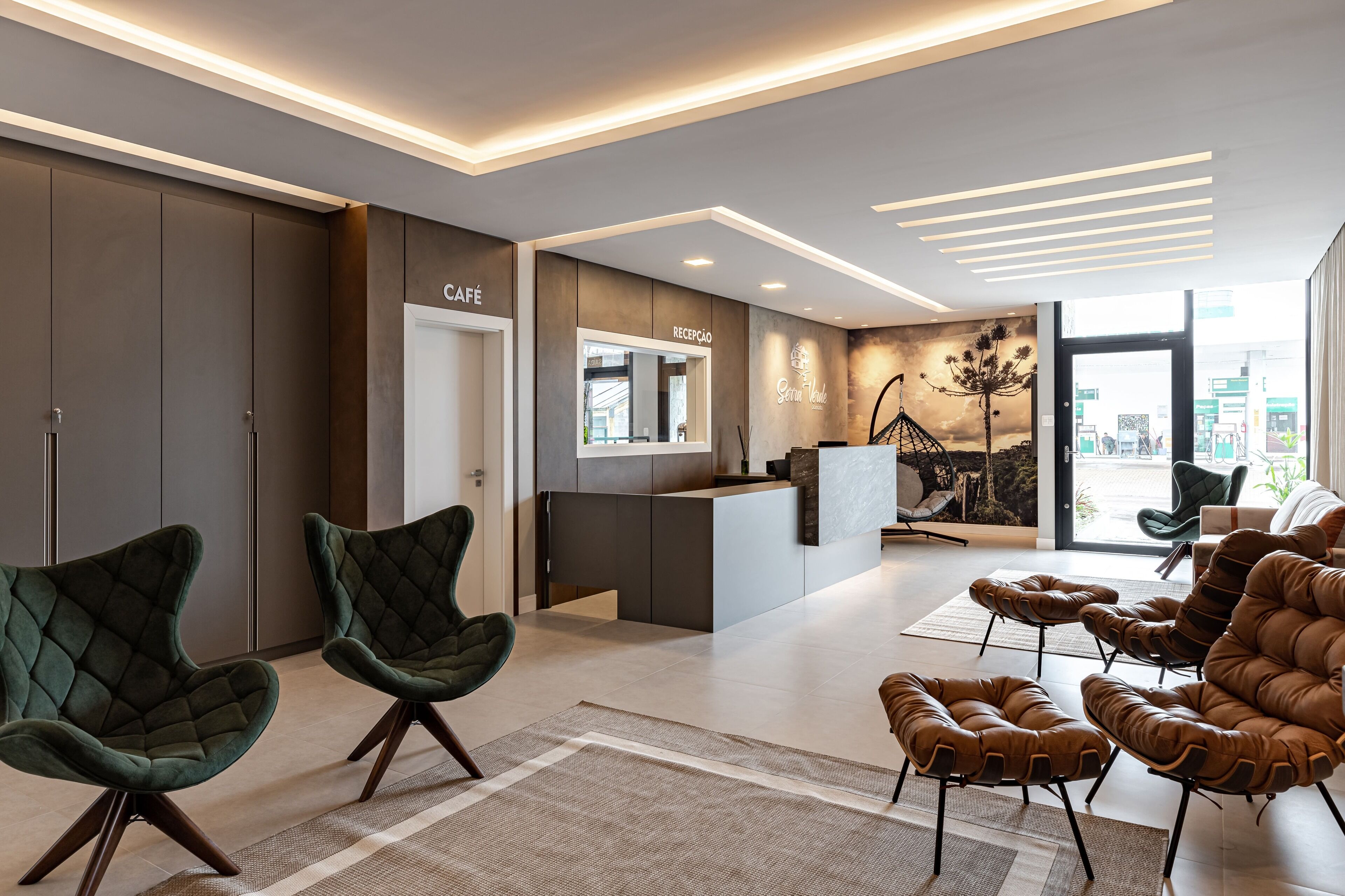 En moderne hotellobby med reception, siddeområde og et stort vindue der giver udsigt over byen.