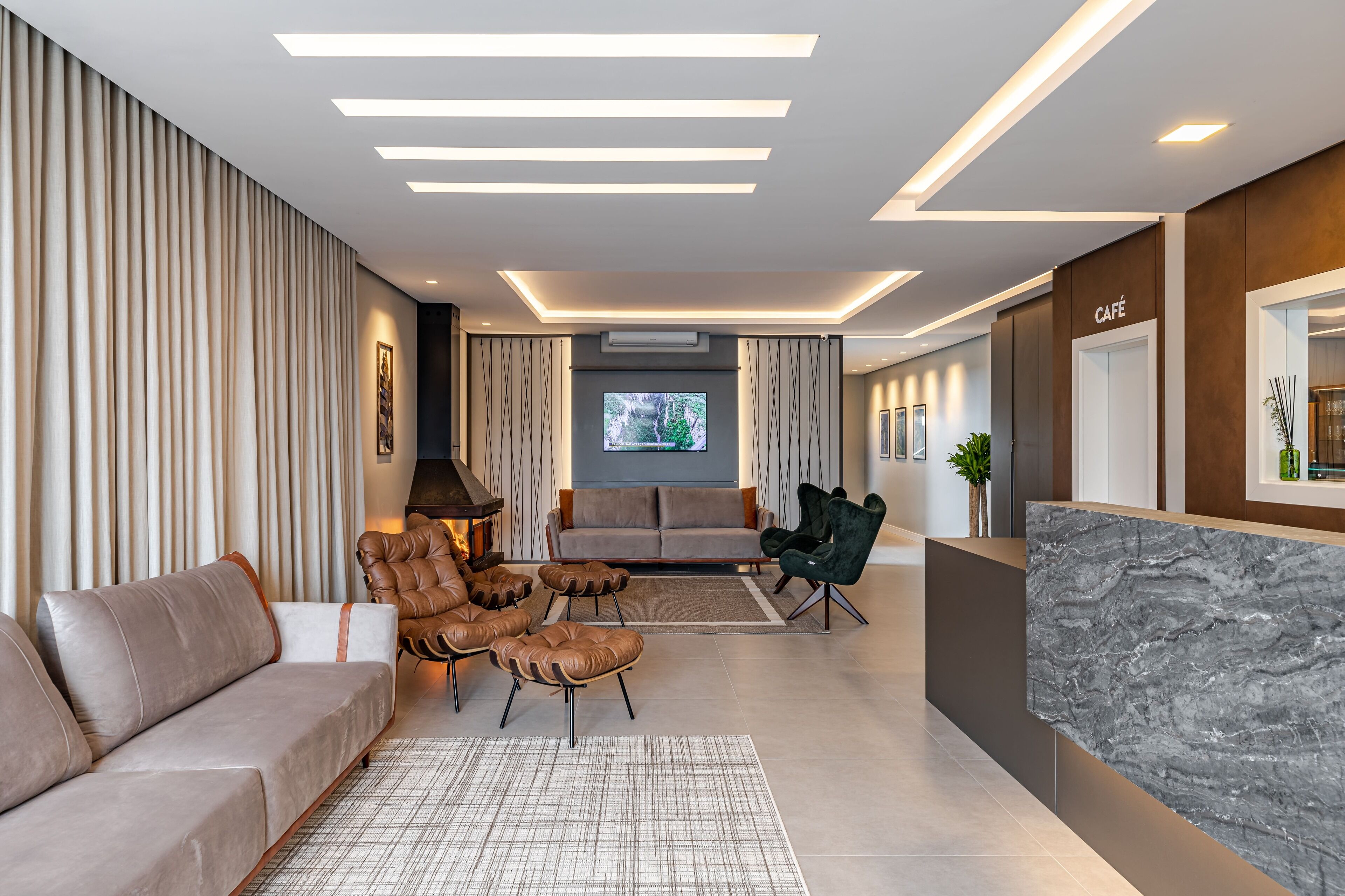 A modern living room with a sofa, leather armchairs, a coffee table, and a TV.