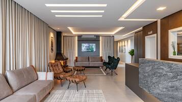 A modern living room with a sofa, leather armchairs, a coffee table, and a TV.