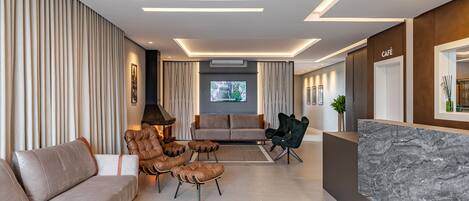 A modern living room with a sofa, leather armchairs, a coffee table, and a TV.