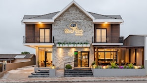 A two-story building with a stone facade, a sign reading "Serra Verde poussada," and a cafe entrance with outdoor seating. - Pousada Serra Verde (Cambara do Sul)