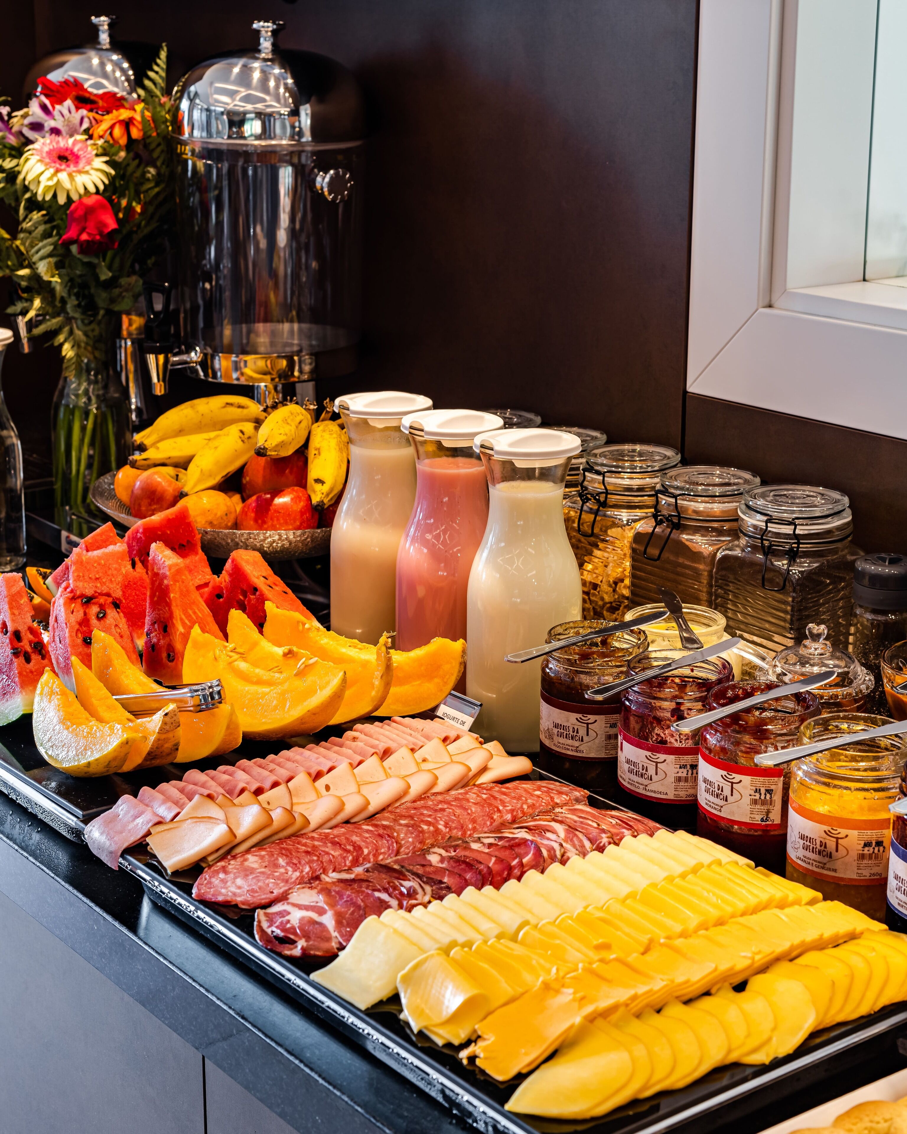 A buffet with various food items including fruits, cheeses, meats, and condiments.
