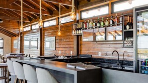 A bar area with wooden beams, a long counter, and bar stools. - Pousada Serra Verde (Cambara do Sul)