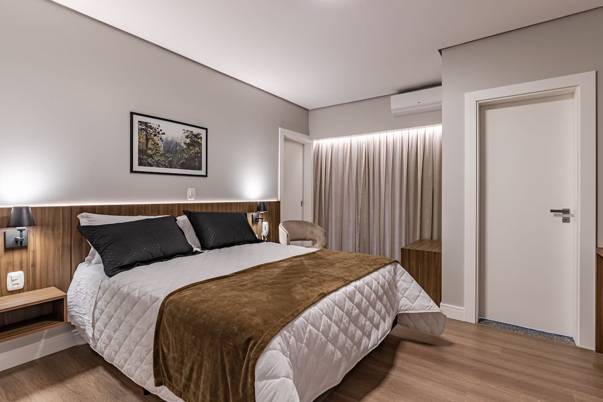 Un dormitorio moderno con una cama grande, mesitas de noche, una silla y una puerta.