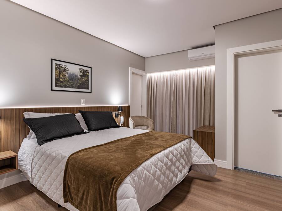 A modern bedroom with a large bed, bedside tables, a chair, and a door.
