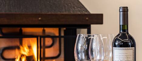 Una mesa de madera con una tabla de embutidos, dos copas de vino y una botella de vino.