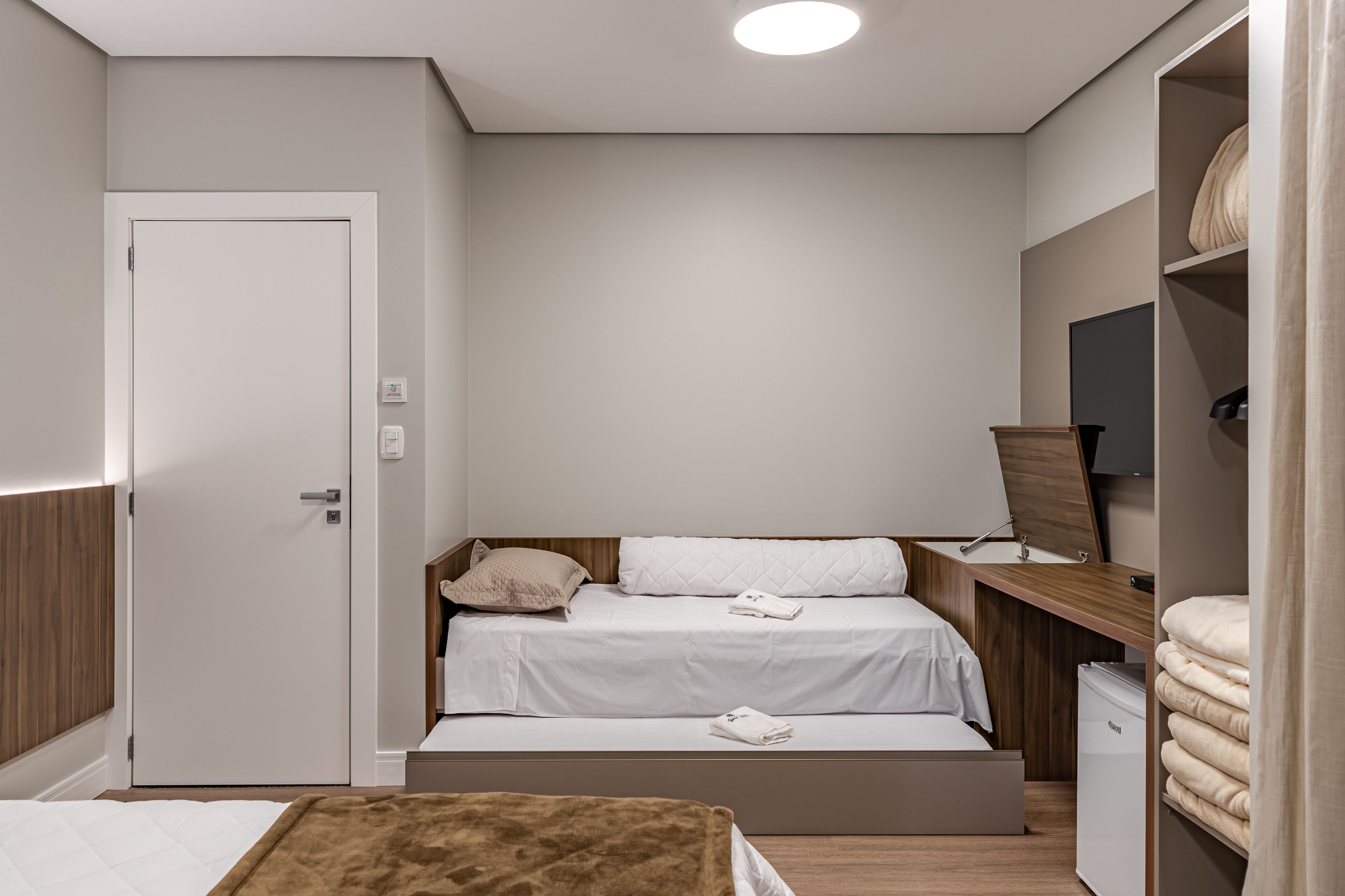 A compact bedroom with a single bed, a small desk, and a wardrobe.