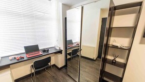 A room with a desk, a chair, a laptop, a pair of headphones, a radiator, and a mirror. - Cosy Ensuite Style Studio Close to University! (Birmingham)