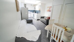 A compact living space with a kitchenette, a sofa, a dining table, and a chair. - Cosy Ensuite Style Studio Close to University! (Birmingham)