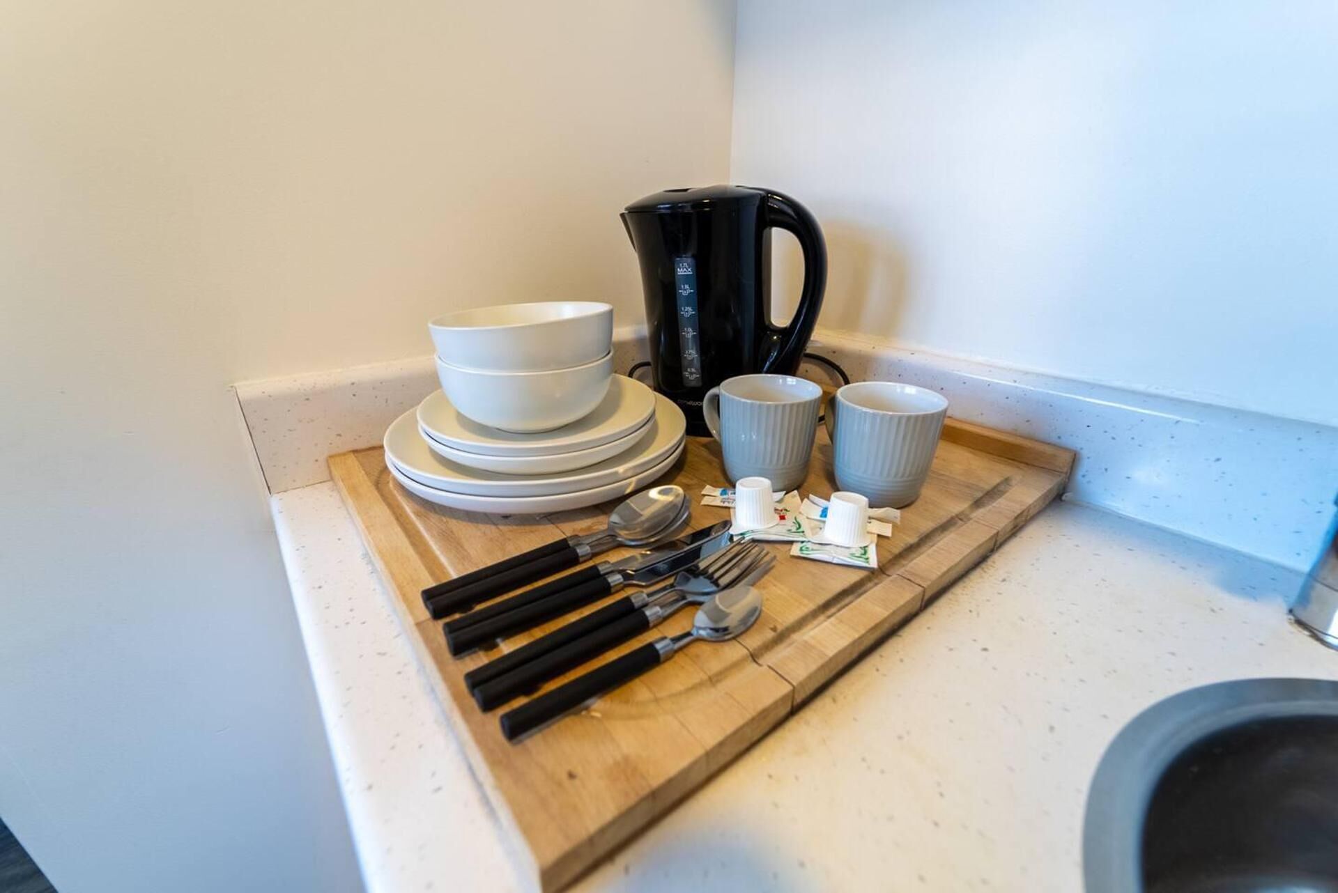 Un comptoir de cuisine avec une machine à café, des assiettes, des bols, des tasses et des ustensiles.
