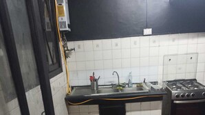 A kitchen with a gas stove, sink, and a red floor.