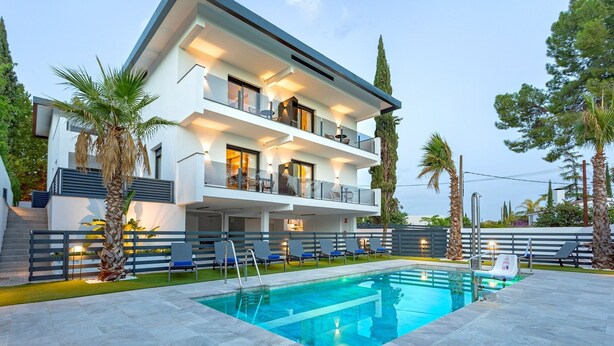 A modern two-story house with a swimming pool, outdoor seating, and palm trees. - Genteel Home Arruzafa II (Cordoba)