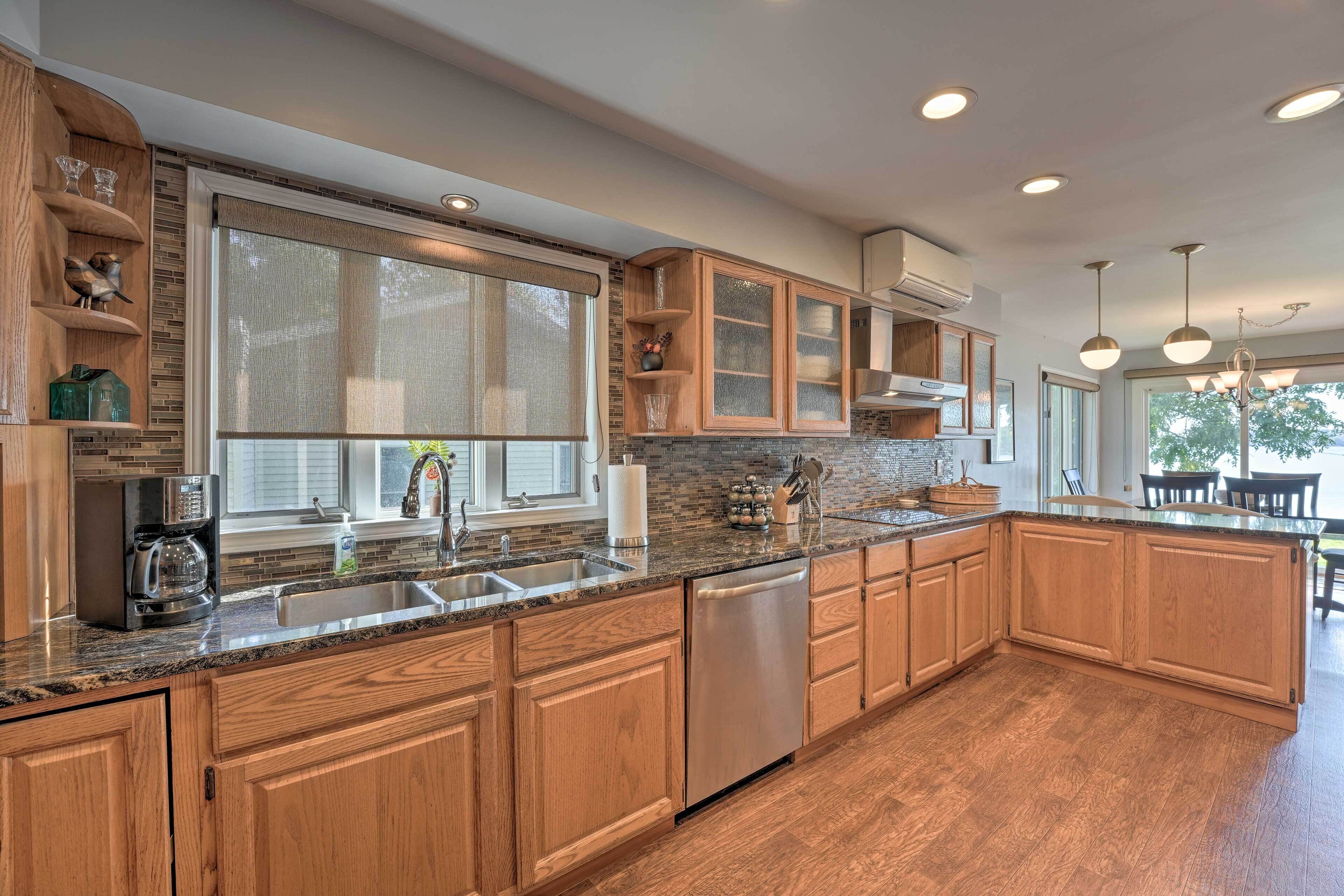 A modern kitchen with wooden cabinets, a granite countertop, and a built-in dishwasher.