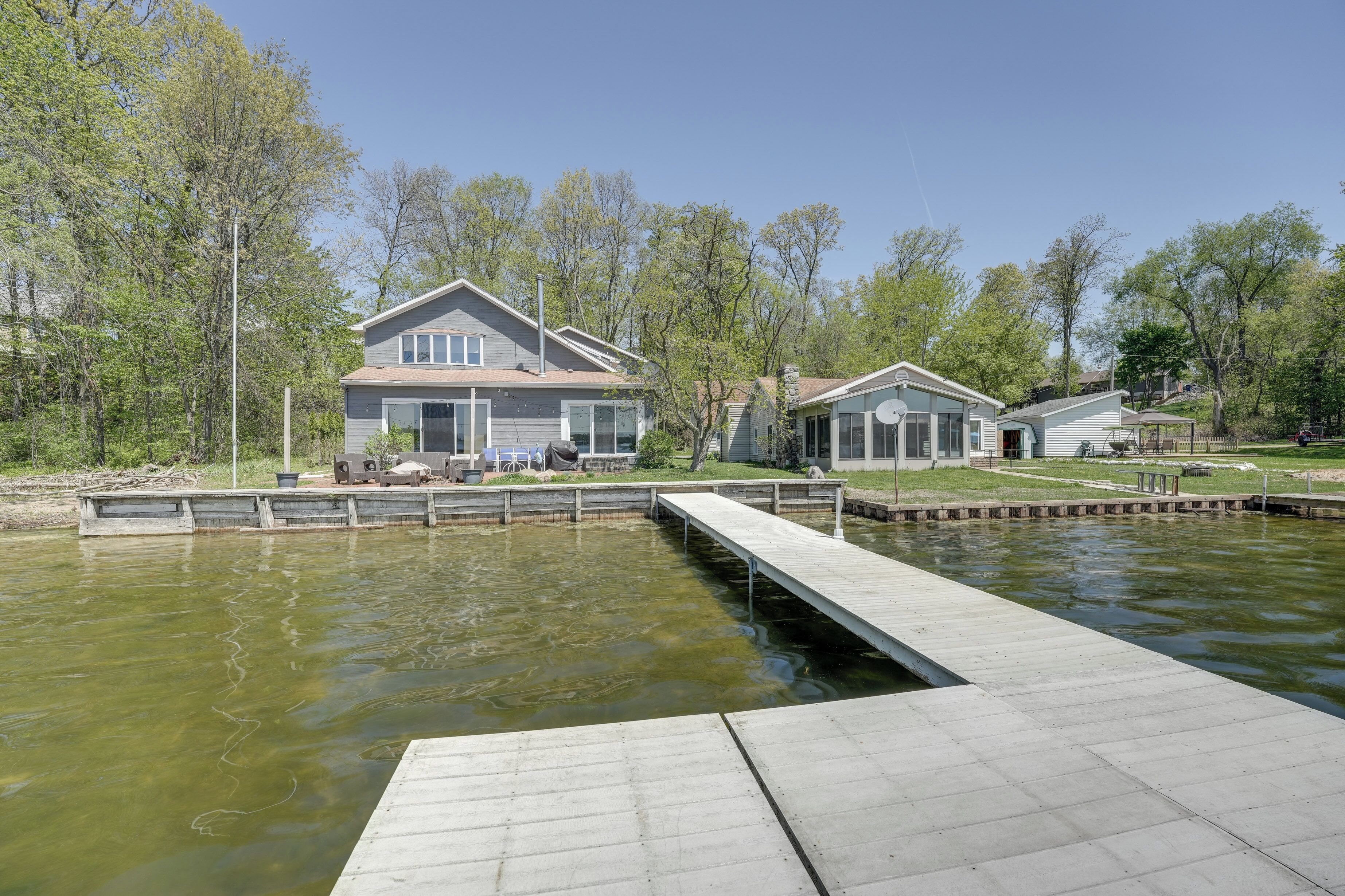Ett bostadsområde med ett hus vid en damm, en brygga och en liten båt.