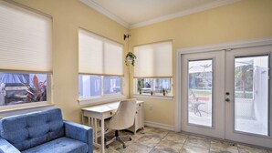 A room with a desk, a blue chair, a hanging plant, and a door with a view of the outside. - 'The Shell House' in Titusville: Pool, Golf Access (Titusville)
