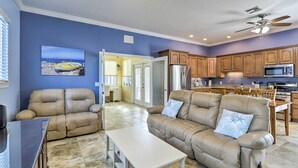 A living room with a beige leather sofa, a white coffee table, and a ceiling fan. - 'The Shell House' in Titusville: Pool, Golf Access (Titusville)
