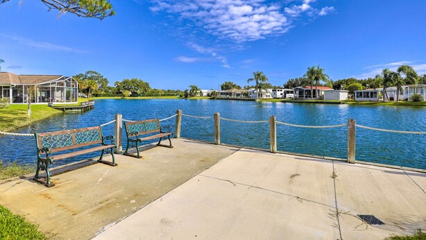 A waterfront park with a concrete walkway, wooden benches, and a rope barrier. - 'The Shell House' in Titusville: Pool, Golf Access (Titusville)