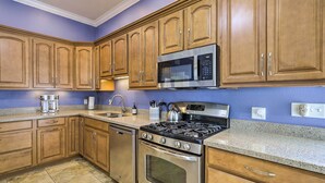 A kitchen with wooden cabinets, stainless steel appliances, and a granite countertop. - 'The Shell House' in Titusville: Pool, Golf Access (Titusville)