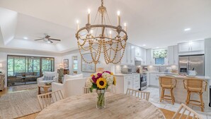A spacious kitchen with modern appliances, a chandelier, and a dining area with a wooden table and chairs. - Stunning renovated cottage in Inlet Cove (Kiawah Island)