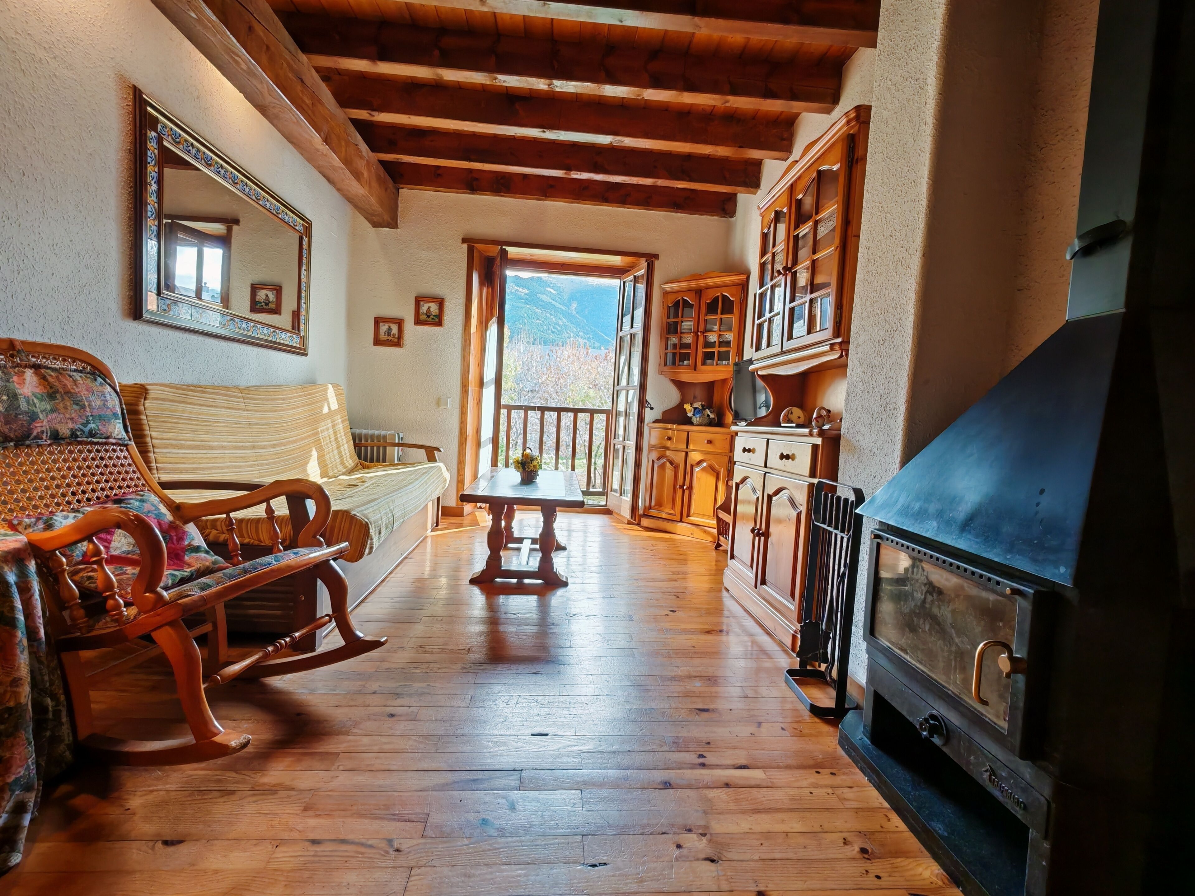 A cozy room with a wooden rocking chair, a sofa, a table, and a large fireplace.