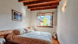 A bedroom with a wooden bed, a nightstand, a window with a view, and a framed picture on the wall. - Spacious apartment with garden Cosmos 1 (Pla de l'Ermita)