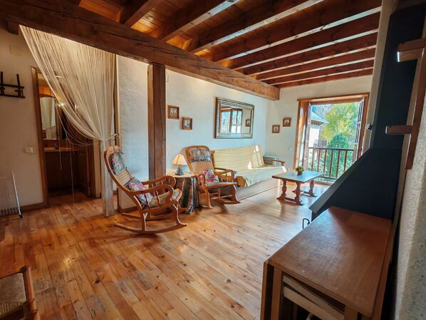 A wooden-floored living area with a sofa, rocking chairs, and a table.