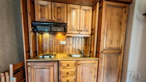 A compact kitchen with wooden cabinets, a gas stove, and a sink. - Spacious apartment with garden Cosmos 1 (Pla de l'Ermita)