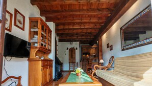 A wooden dining table with chairs, a television, wooden cabinets, and a sofa in a room with wooden beams on the ceiling. - Spacious apartment with garden Cosmos 1 (Pla de l'Ermita)