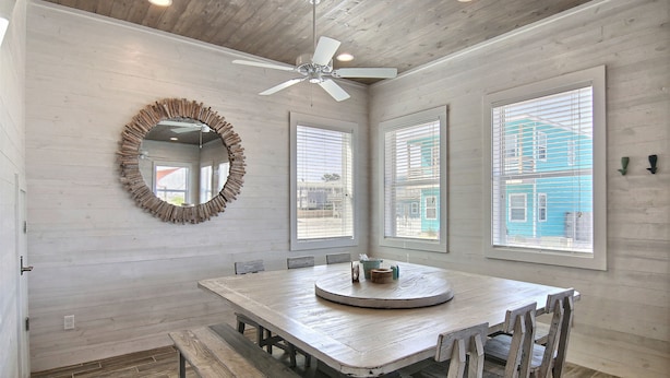 A dining area with a wooden table, benches, and a ceiling fan. - The Beach Buoy by Silver Sands Vacation Rentals (Port Aransas)