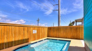 A small, rectangular outdoor swimming pool with a wooden fence surrounding it. - The Beach Buoy by Silver Sands Vacation Rentals (Port Aransas)