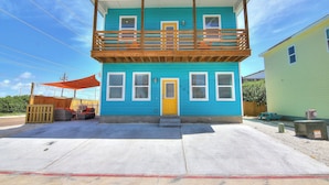 A two-story house with a balcony, a front door, and a small porch area. - The Beach Buoy by Silver Sands Vacation Rentals (Port Aransas)