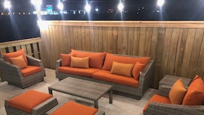 An outdoor seating area with wicker furniture and orange cushions. - The Beach Buoy by Silver Sands Vacation Rentals (Port Aransas)