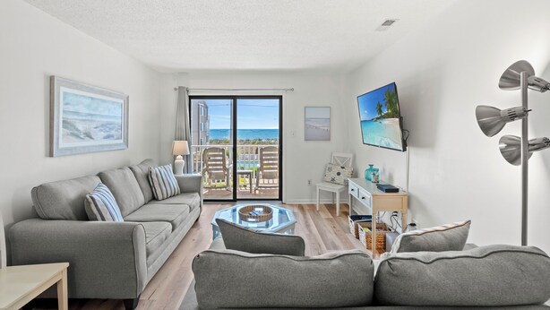 A modern living room with a grey sofa, a coffee table, and a TV on the wall.