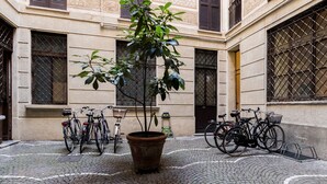 A courtyard with bicycles parked around a central potted plant. - JOIVY Lovely Flat For 5 Close To Sforzesco Castle (Milan)
