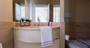 Ein Badezimmer mit einem beigefarbenen Waschtisch, einem weißen Handtuch, einem Spiegel und einer Toilette.