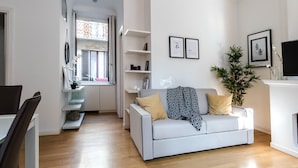 A modern living room with a white sofa, a fireplace, and a TV. - JOIVY Lovely Flat For 5 Close To Sforzesco Castle (Milan)