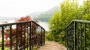 Un escalier orné de rampes en métal travaillées, menant à un point de vue panoramique sur un lac et des montagnes.