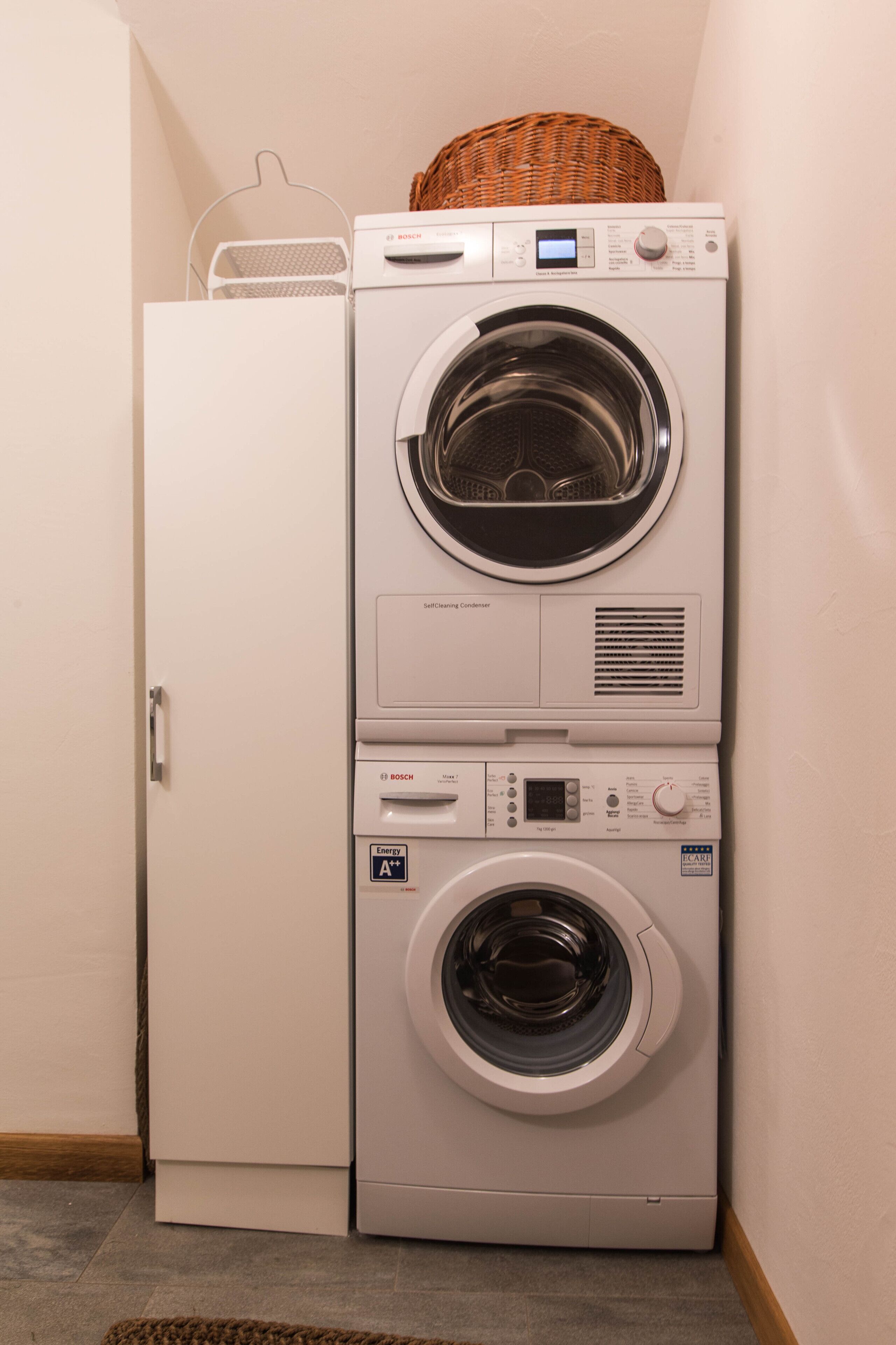 A stacked washer and dryer unit with a basket on top, a control panel, and an energy efficiency label.