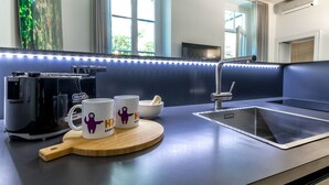 A modern kitchen with a stainless steel sink, a coffee maker, and two mugs on a wooden board. - JOIVY Superb 1Bed Apt In Brera (Milan)