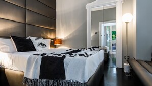 A modern bedroom with a large bed, a bedside table with a lamp, a mirror, and a view of a balcony. - JOIVY Superb 1Bed Apt In Brera (Milan)
