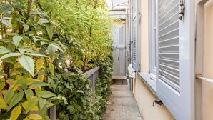 A narrow alleyway with a metal railing, a concrete path, and a building with shutters. - JOIVY Superb 1Bed Apt In Brera (Milan)