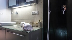 A modern bathroom with a glass countertop, a white sink, and a black shower enclosure. - JOIVY Superb 1Bed Apt In Brera (Milan)